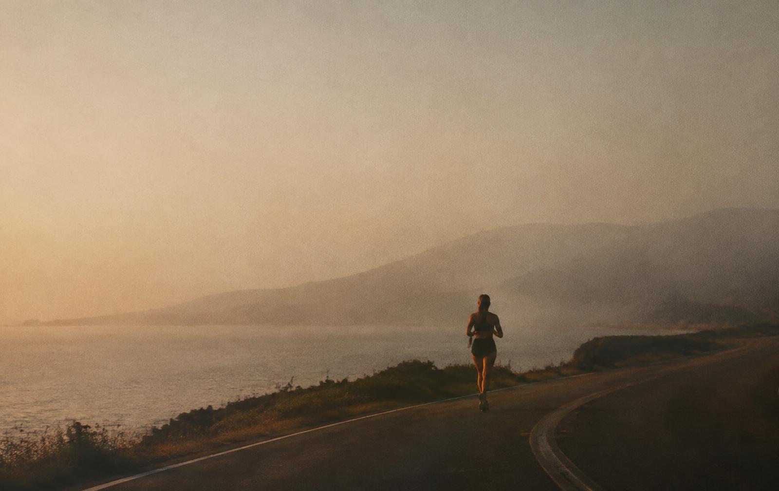 A lone runner on a coastal road at dawn